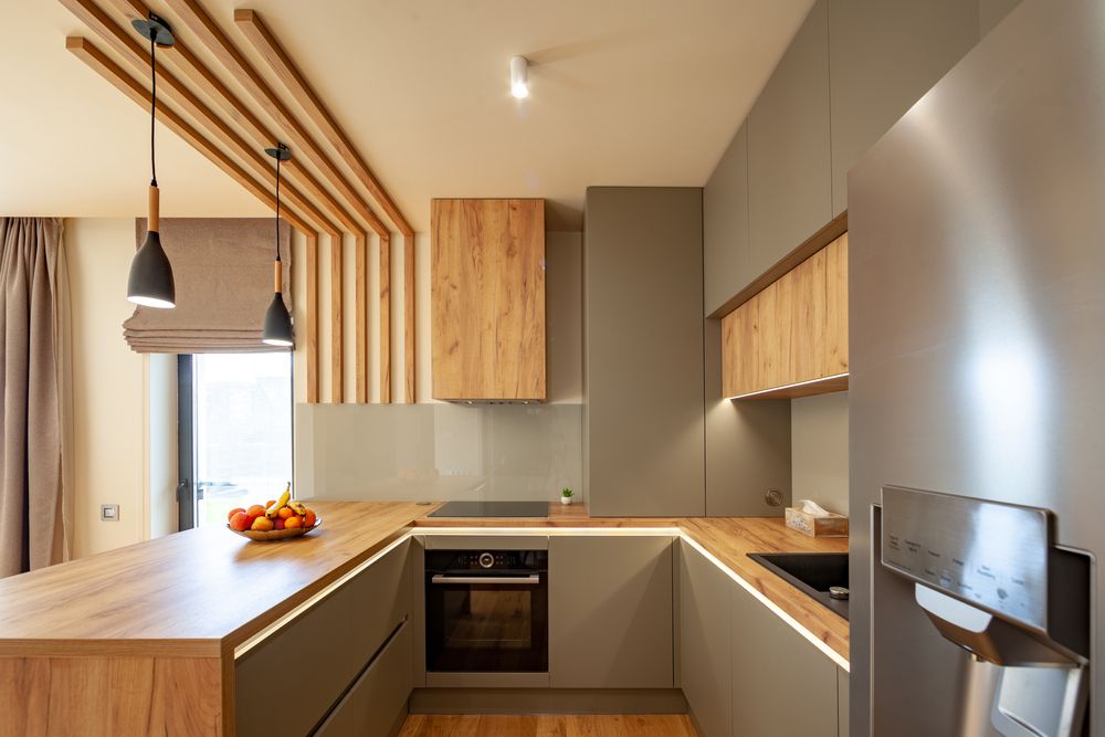 A close up of a gray kitchen with a U shaped kitchen island